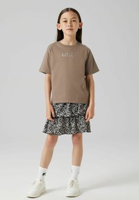 Brun bomullströja med texten "LOVE", lager av svart och vit leopardmönstrad kjol, samt vita sneakers med ribbade vita strumpor.