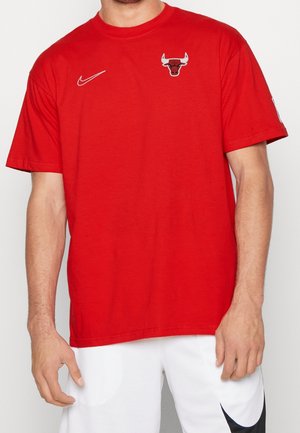 T-shirt Nike rouge avec col rond, manches courtes, arborant un logo des Chicago Bulls sur la poitrine. Tissu doux et texturé, coupe décontractée.