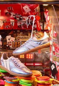 Baskets argentées exposées à l’intérieur d’une machine à pince d’arcade sur le thème de Las Vegas, remplie de jetons en plastique colorés et d’images de casino.