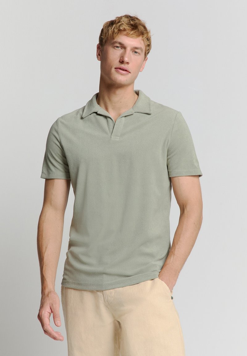 Korte mouwen polo shirt in lichtgroene stof, met een zachte textuur, open kraag en rechte zoom, gecombineerd met lichtbeige broek.