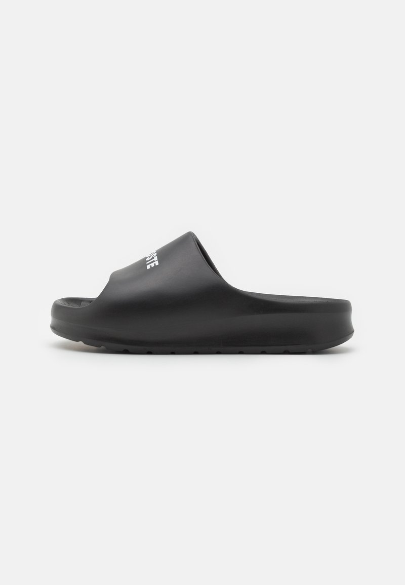 Sandalias negras sin hebilla con superficie de goma suave, punta redondeada, suela texturizada y logo blanco en la correa.