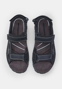 Mustad musta värvi sandaalid reguleeritavate rihmadega ja pehme halli sisetallaga. Omab tekstuurset viimistlust, kontrastset valget õmblust ja lõikega disaini.