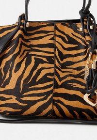 Sac à main structuré en imprimé tigre orange et noir. Fabriqué en cuir synthétique lisse, il est doté de ferrures dorées et de deux anses de transport.