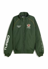Zelena bomber jakna s patent zatvaračem, rebrastim manšetama i donjim rubom. Tekst na rukavima: "TURBO" i "DUH." Logotipi na prsima u žutoj i crvenoj boji.