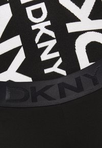 Tissu DKNY en noir et blanc avec de grandes lettres et une ceinture noire arborant un texte discret du logo DKNY.