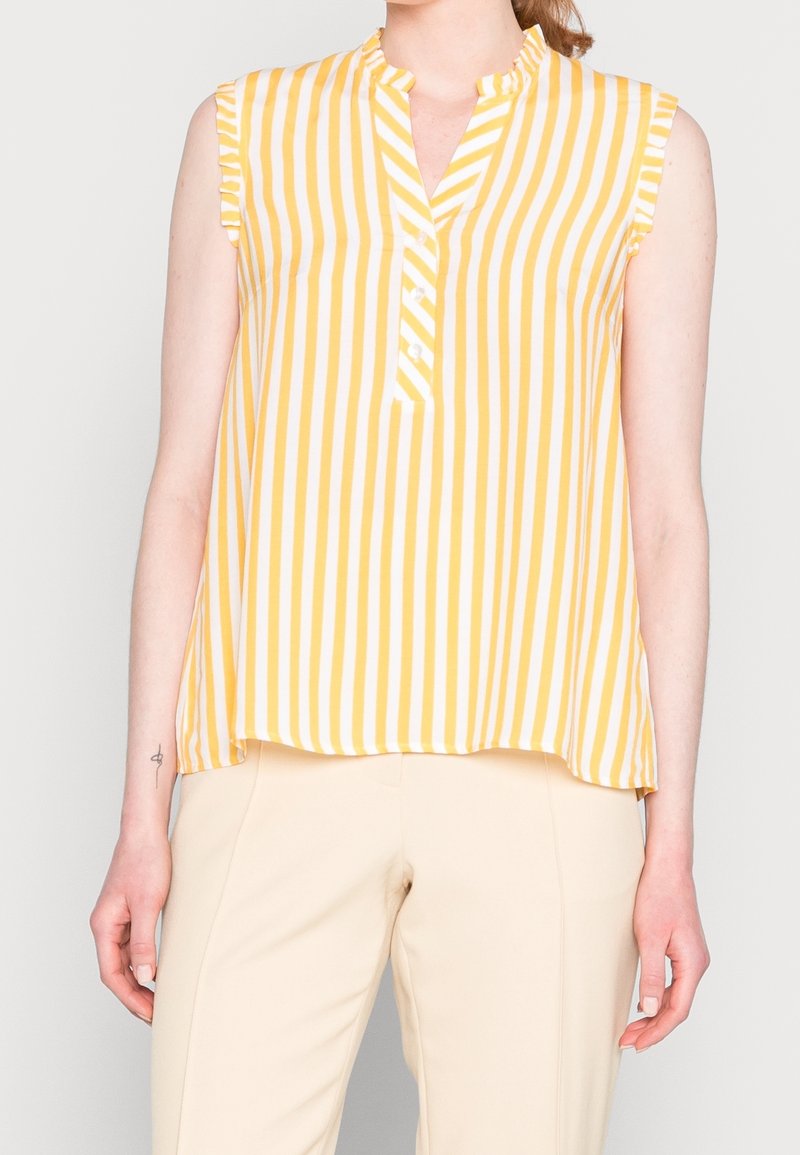 Blusa senza maniche a righe verticali gialle e bianche, con colletto alla cinese, maniche arricciate e una piaghetta con bottoni sul collo.