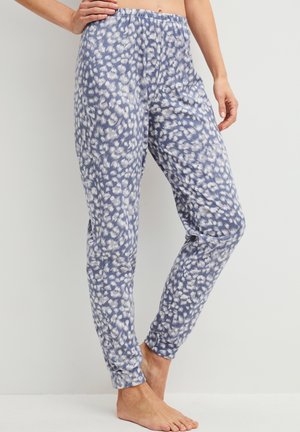 Weit geschnittene blau-weiß gepunktete Hose mit elastischem Bund und Bündchen, barfuß getragen von einer Person vor einfachem Hintergrund.