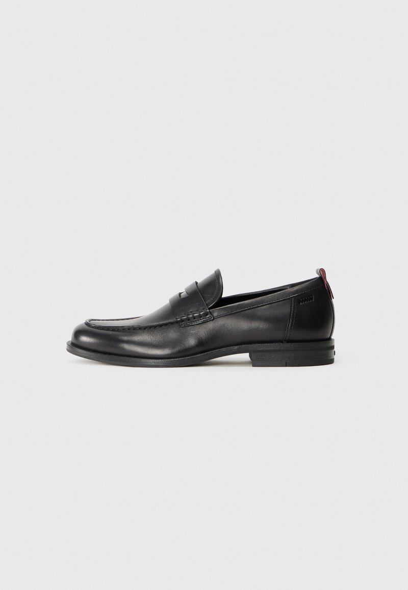 Black leather loafers with a rounded toe, stitched detailing, and a small red accent at the heel. Low-profile rubber sole.