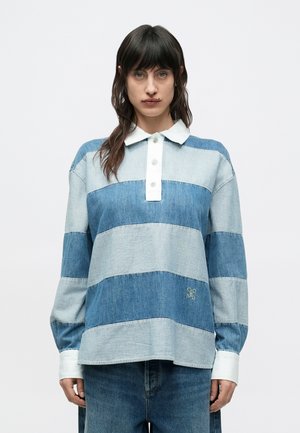 Chemise en denim avec un design à rayures bleues et bleu clair, col, patte de boutonnage à trois boutons, et détail de logo brodé à l'ourlet. Manches longues.