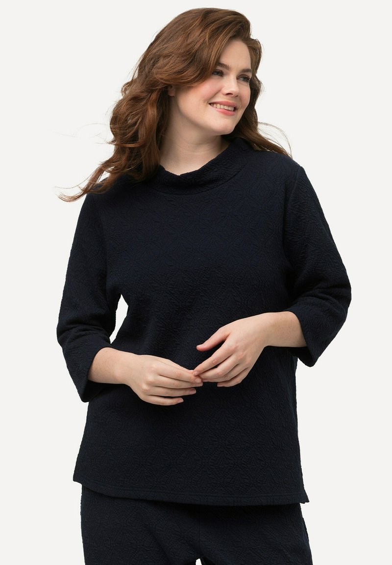 T unica blu navy con un motivo testurizzato, caratterizzata da un collo a imbuto e maniche a tre quarti, realizzata in un tessuto morbido.