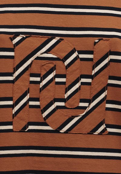 Ύφασμα ριγέ σε καφέ, μαύρο και άσπρο με ένα ραμμένο σημείο που σχηματίζει τα αλληλοσυνδεδεμένα γράμματα «n» και «u» με το ίδιο μοτίβο.