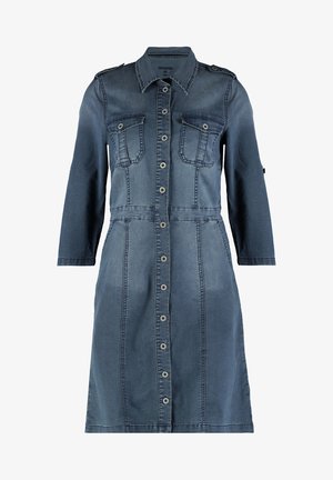 Tumedast siniselt denimpukud, pikkade varrukatega, nööbist ees, kahe rinna taskuga ja figuurile sobiv talje. Omab klassikalist kraed ja õmblusdetailide lisasid.