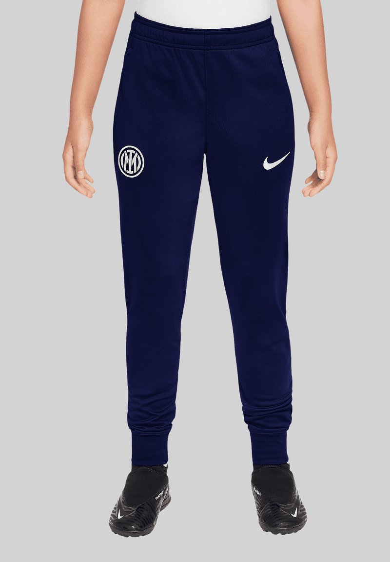 Marineblauwe sweatpants met een elastische tailleband, een witte Nike swoosh en een rond wit logo op het linkerbeen. Zacht materiaal met taps toelopende manchetten.