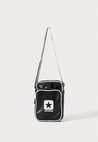Borsa a tracolla nera in materiale sintetico con rifiniture bianche, dotata di una tasca frontale con cerniera e un logo Converse stampato in bianco con una stella.