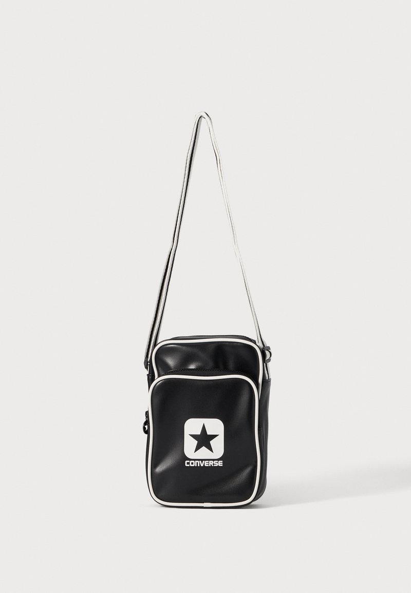 Borsa a tracolla nera in materiale sintetico con rifiniture bianche, dotata di una tasca frontale con cerniera e un logo Converse stampato in bianco con una stella.