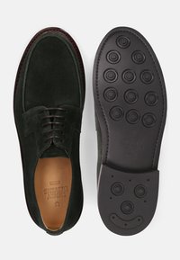 Donkergroene suède schoenen met een ronde neus en vetersluiting. De buitenzool heeft ronde indeuken en geperste merkdetails.