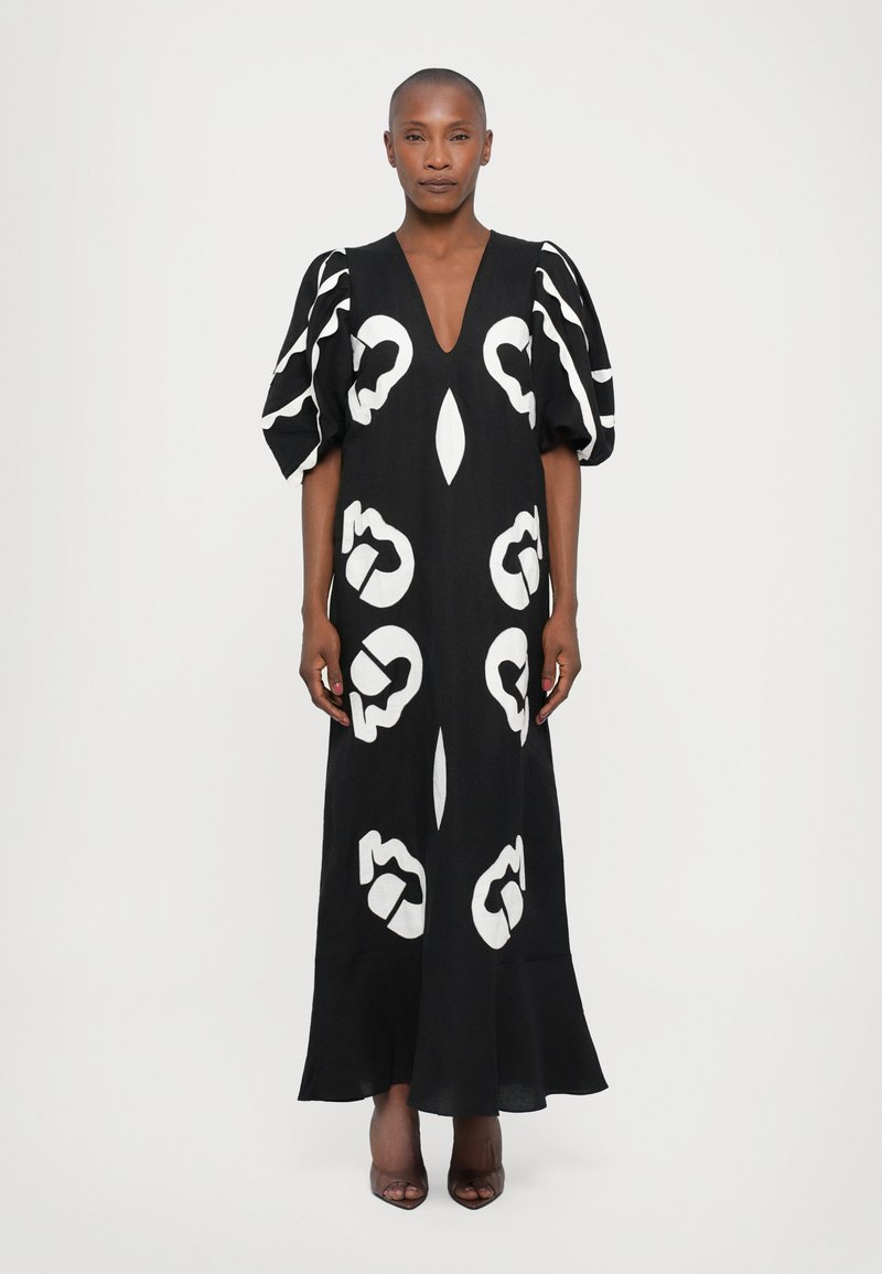 Rochie maxi neagră cu modele abstracte albe, decolteu adânc în V și mâneci bufante voluminoase. Țesătură netedă cu tiv evazat.