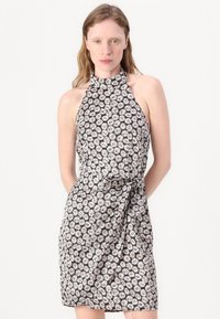 Halter-neck dress with a fitted silhouette, featuring a black background and white daisy floral pattern. Smooth fabric with a tied waist detail.