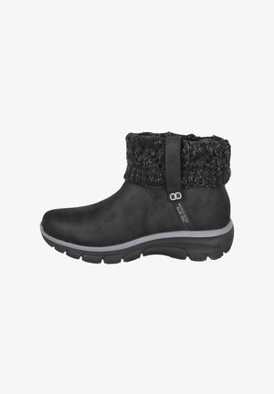 Botas negras de tobillo con un upper sintético liso y un puño de punto texturizado, que presentan una suela gris y una lengüeta para facilitar su uso.