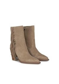 Botas de tobillo de ante beige con punta afilada, cremallera lateral y detalle de flecos con borlas adornados con tachuelas. El tacón cuadrado añade estabilidad.