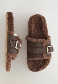 Sandales brunes moelleuses avec deux brides, dotées d'un tissu texturé, d'une boucle dorée et d'une semelle en liège. Matériau doux et pelucheux partout.