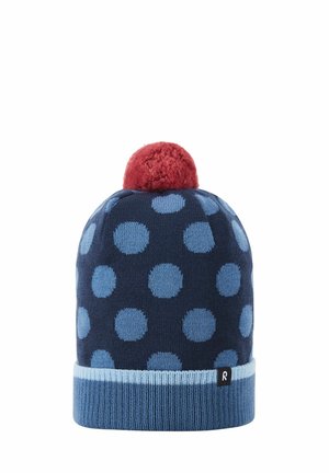 Knit beanie in navy with large blue polka dots, featuring a red pom-pom on top and a light blue ribbed cuff with a small black logo.