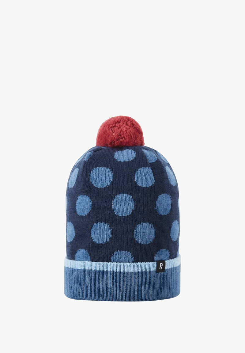 Knit beanie in navy with large blue polka dots, featuring a red pom-pom on top and a light blue ribbed cuff with a small black logo.