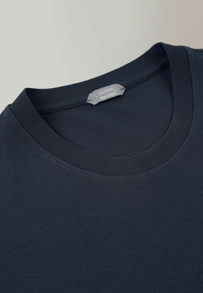 T-shirt en coton bleu marine avec un col rond, texture lisse et encolure cousue. Présente une étiquette indiquant "Zanone icc.cotton."