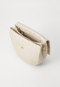 Beige leren handtas met reliëf logo ontwerp, gouden hardware en dubbele vakken in de binnenzijde. Soepele textuur en ronde vorm.