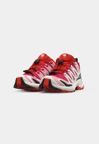 Scarpe sportive rosse e rosa con parte superiore in rete, superficie texturizzata, lacci elastici e suola in gomma. Presentano un logo distintivo e un tallone a contrasto.