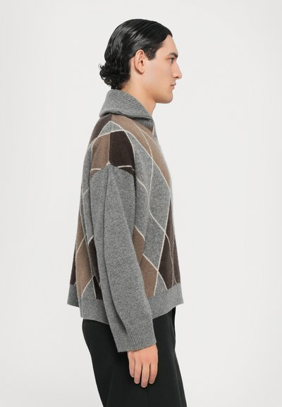 Suéter de punto gris con un cuello con solapa, que presenta un patrón geométrico en forma de diamante en tonos de marrón y crema. Textura suave, corte relajado.