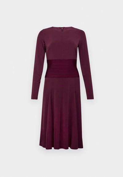 Μπορντό φόρεμα με μακριά μανίκια, εφαρμοστό κορσέ, υφασμάτινη λεπτομέρεια στη μέση και φουσκωτή φούστα. Λείος ύφασμα με κλείσιμο με φερμουάρ στην πλάτη.