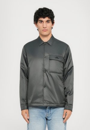 Graue, gepolsterte Jacke mit Kragen, vorderem Knopfverschluss und einer Brusttasche mit Logo. Glatte, glänzende Textur.