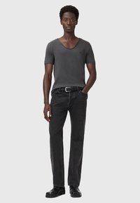 T-shirt grigio a maniche corte con scollo a V abbinato a jeans neri a gamba dritta, completato da una cintura nera e scarpe nere eleganti.