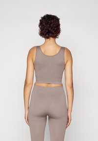 Brown ribbed crop top paired with high-waisted matching leggings. The fabric has a soft texture and fitted design, visible seams, and a simple silhouette.