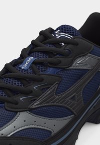 Σκούρο μπλε και μαύρο αθλητικό παπούτσι από δίχτυ με μαύρα κορδόνια και γκρι συνθετικές επιστρώσεις, με στιλιζαρισμένο λογότυπο στο πλάι.