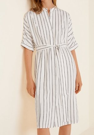 Robe blanche à boutons avec des rayures verticales noires, manches courtes, taille ceinturée, longueur genou, texture de tissu lisse.