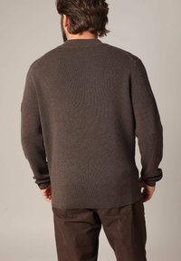 Pull en maille côtelée marron avec des manches longues et un col rond, présentant une coupe décontractée et une texture subtile. Vue arrière.