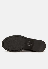 Semelle de chaussure noire en caoutchouc texturé, présentant une forme incurvée et un léger talon. Les marquages incluent "Floria" et la taille 37.