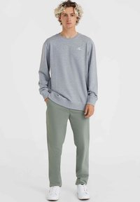 Grijze sweatshirt met lange mouwen, een ronde halslijn en ribgebreide manchetten, gecombineerd met lichtgroene broek en witte sneakers.