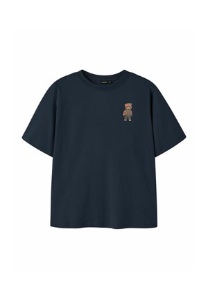 T-shirt bleu marine à manches courtes avec un petit motif d'un ours en peluche portant une veste marron sur la poitrine gauche.