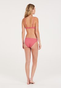 Bikini rosa a coste con spalline regolabili e chiusura a gancio. Il top ha un taglio dritto, mentre i pantaloni sono a vita media con una finitura liscia.