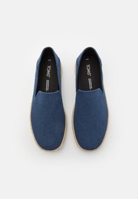 Scarpe slip-on blu navy realizzate in tessuto con una finitura testurizzata e suola in juta naturale. Presentano una soletta nera imbottita con il marchio 'TOMS'.
