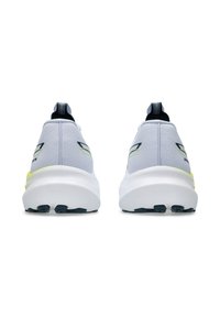 Une paire de chaussures de sport gris clair avec des semelles blanches et des languettes noires, vues de l'arrière sur un fond blanc.