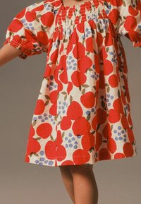 Vestido de patrón de frutas rojas con mangas abullonadas, escote fruncido y un corte holgado. Fabricado con tejido ligero que presenta manzanas, uvas y hojas.
