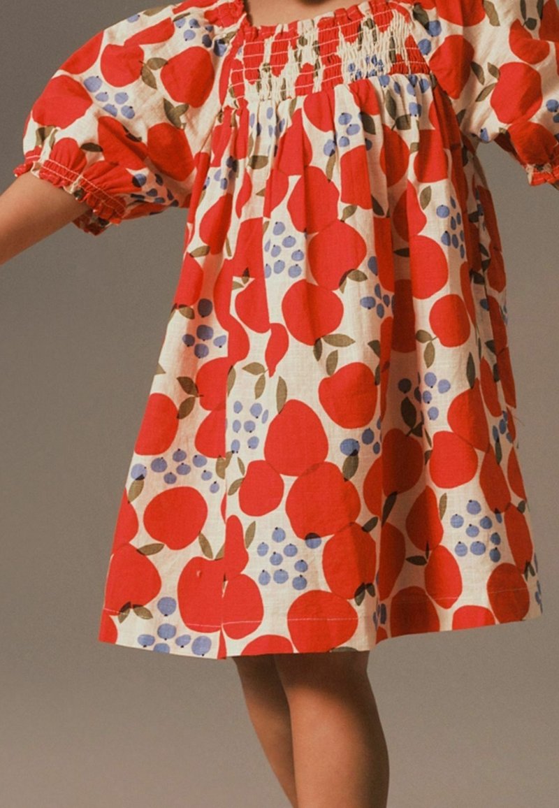 Vestido de patrón de frutas rojas con mangas abullonadas, escote fruncido y un corte holgado. Fabricado con tejido ligero que presenta manzanas, uvas y hojas.