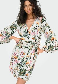 Blumiges Wickelkleid mit langen Glockenärmeln, einem tiefen V-Ausschnitt und einer Bindegürtel. Hergestellt aus leichtem Stoff mit lebhaften grünen und pinken Mustern.