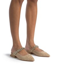 Beżowe zamszowe buty typu slingback z noskiem w kształcie szpica, ozdobione koralikowym paskiem na podbiciu oraz niskim, płaskim obcasem.