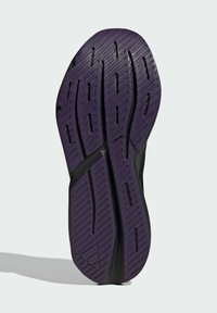 Black athletic shoe sole with a purple rubber layer. Features a textured tread with grooves for traction and flexibility.