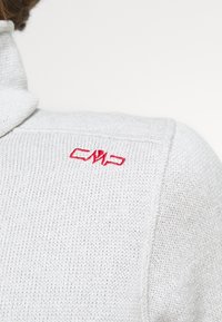 Maglione a collo alto di colore grigio chiaro in maglia, con il logo "CMP" ricamato di rosso sulla spalla. Il tessuto sembra morbido e strutturato.